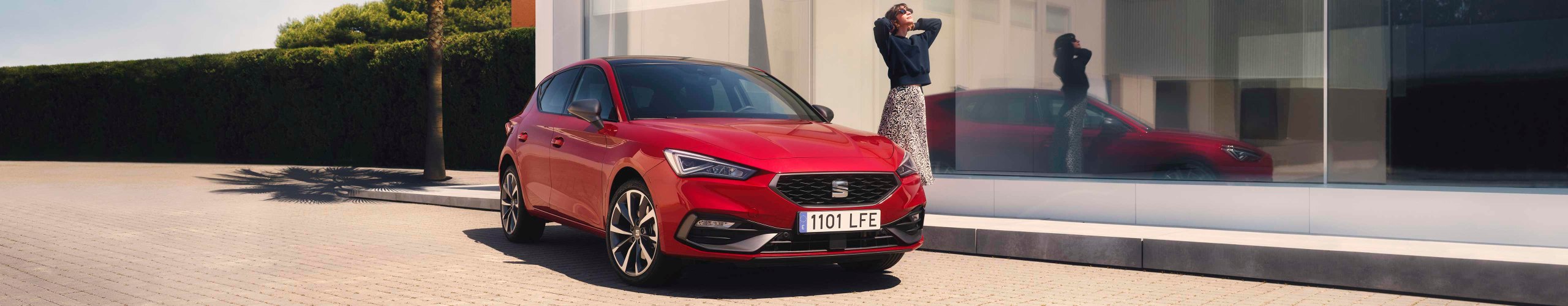 Woman standing next to SEAT Leon desire red colour