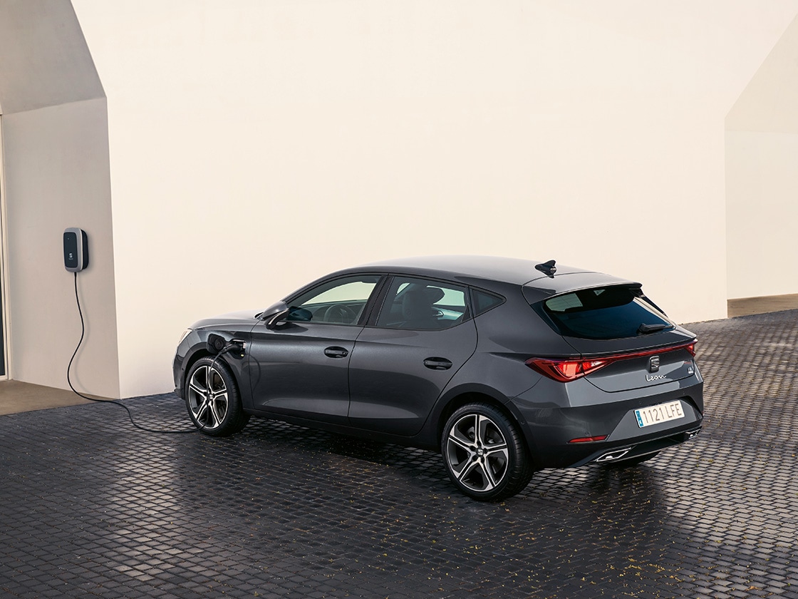 SEAT Leon hatchback plug in hybrid electric vehicle. Parked and charging outdoors, featuring spoke alloy wheels, interior ambient lighting and heated front SEATs for optimal comfort.
