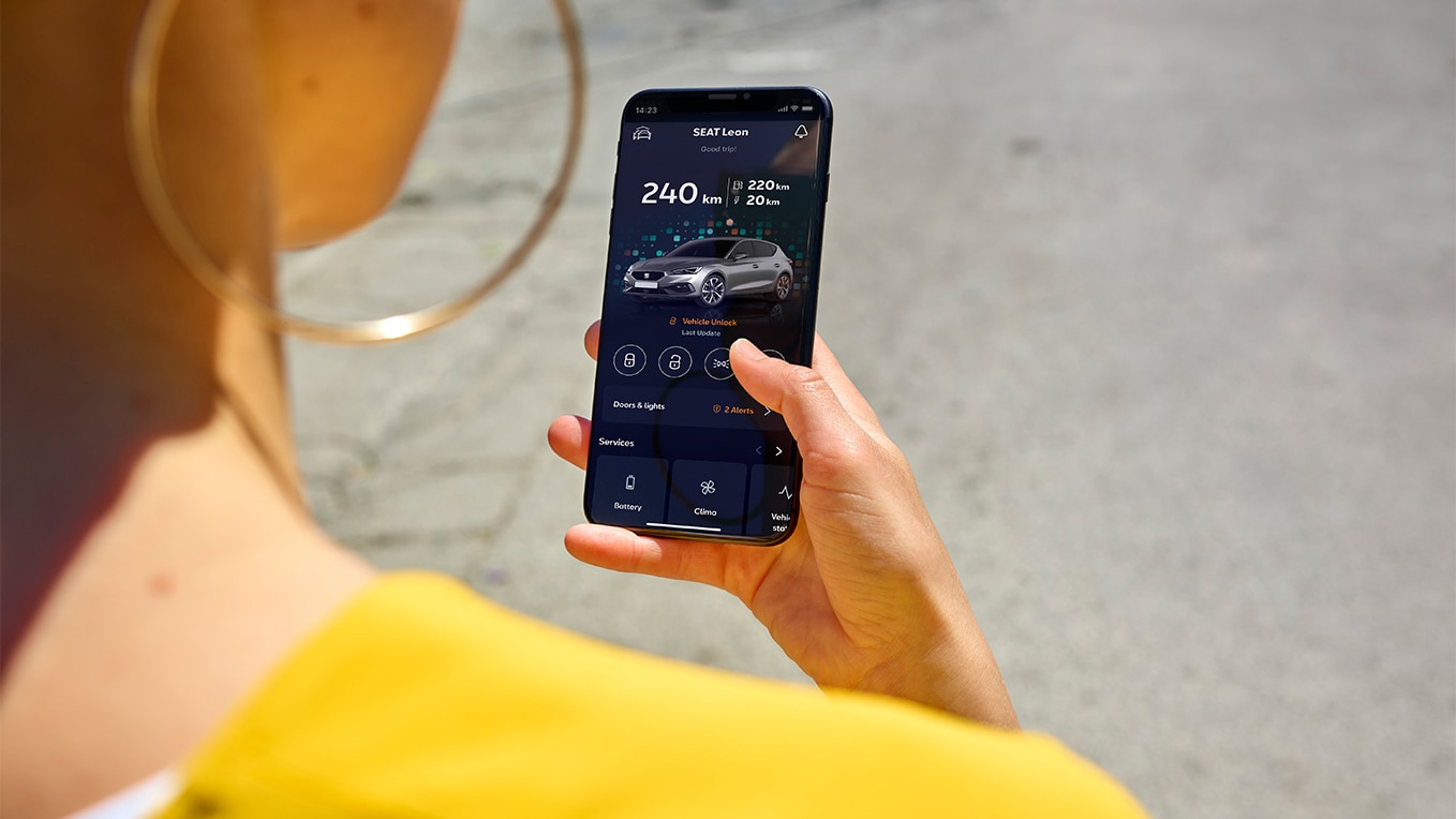 A person holding a smartphone using the SEAT App, a feature of SEAT connect, for remote access and vehicles features.