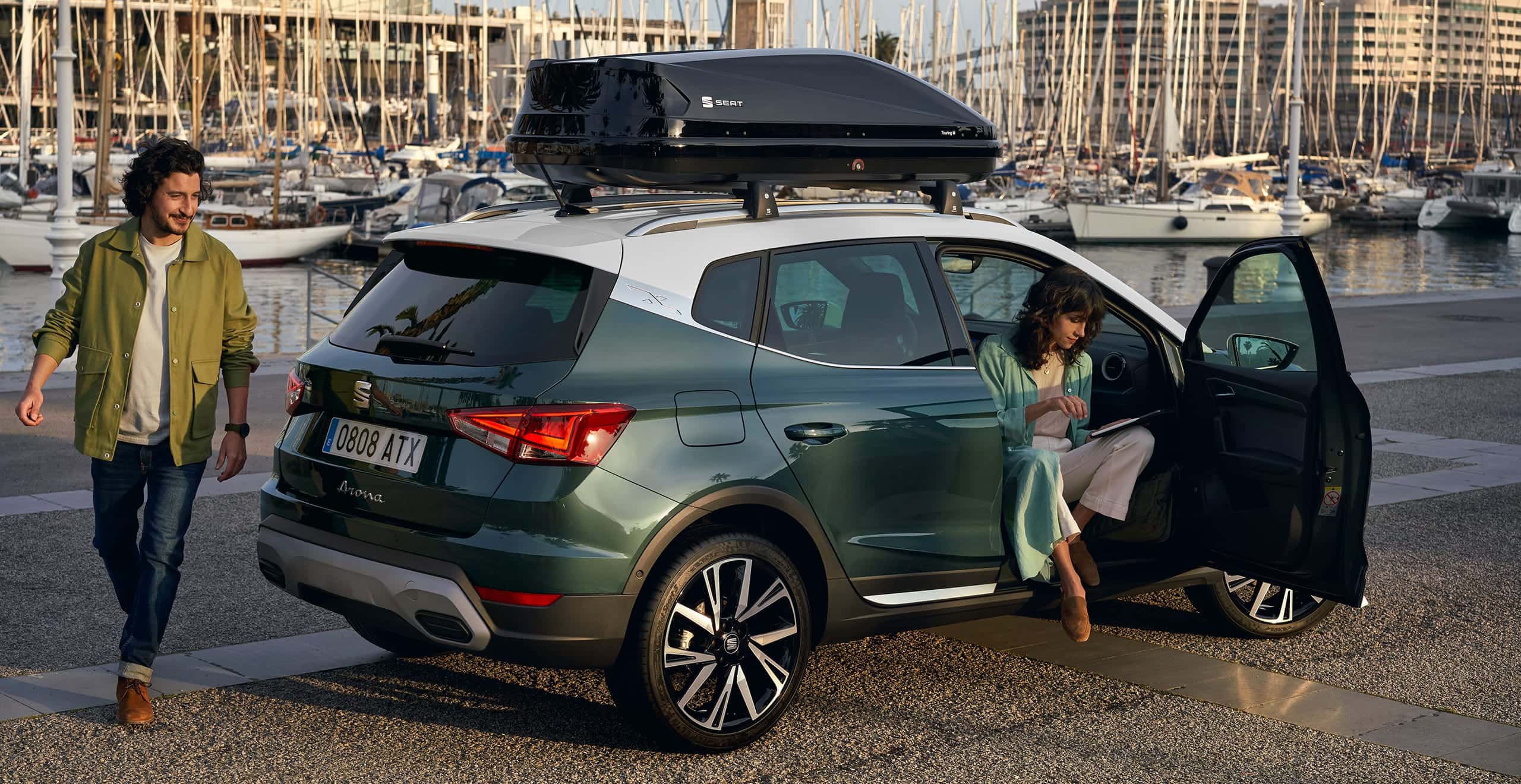 Woman sitting on SEAT Arona dark camouflage colour and white roof