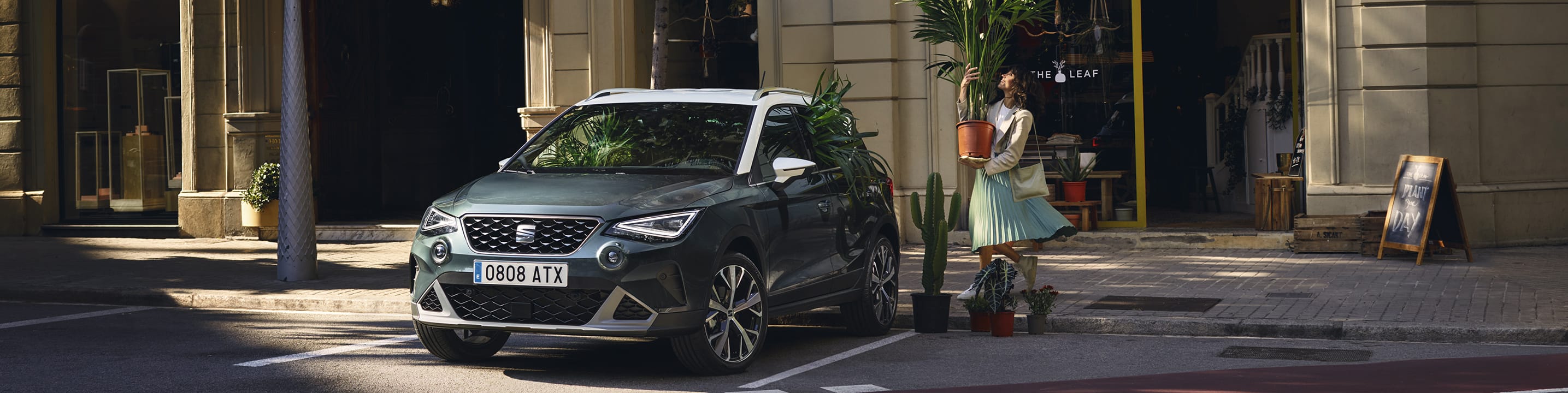 Woman with a plant walking to SEAT arona dark camouflage colour