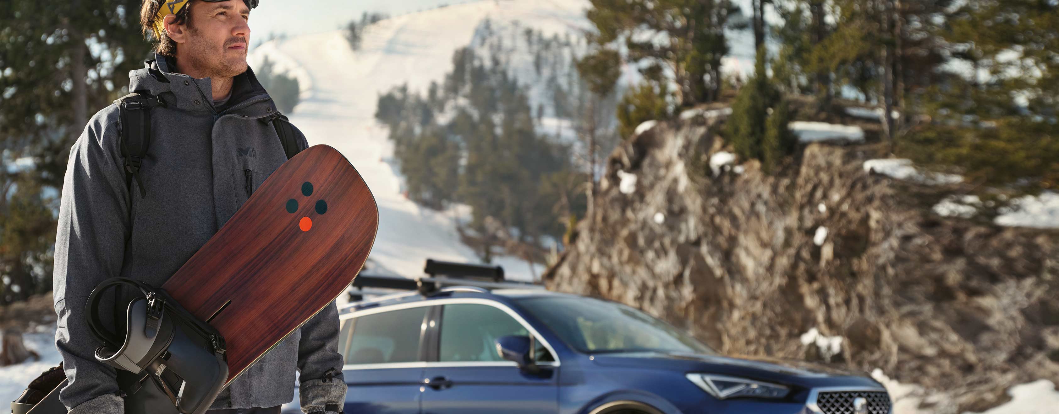 Man standing next to SEAT Tarraco atlantic blue colour with a ski rack.