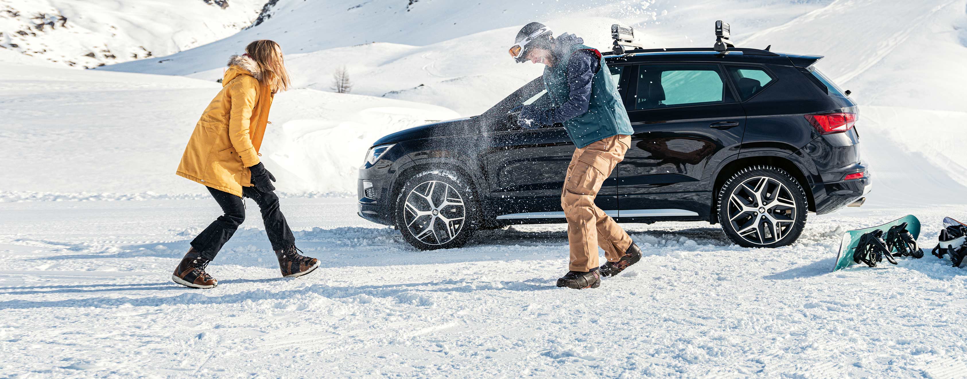 Friends playing with snow next to SEAT Tarraco deep black colour .